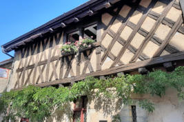 Châteauneuf en Auxois : fenêtre fleurie dans façade de maison à pan de bois
