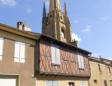 Marciac : maison à pans de bois et volets fermés et clocher de l'église Notre-Dame de l'Assomption