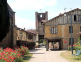 Tillac : rue principale avec maisons à pan de bois et tour médiévale