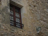 Saint Jean d'alcas : cité médiévale-sculpture à côté de fenêtre à meneaux moderne 