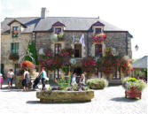 Rochefort en Terre - place du village avec parterres de fleurs et maison fleurie et fontaine
